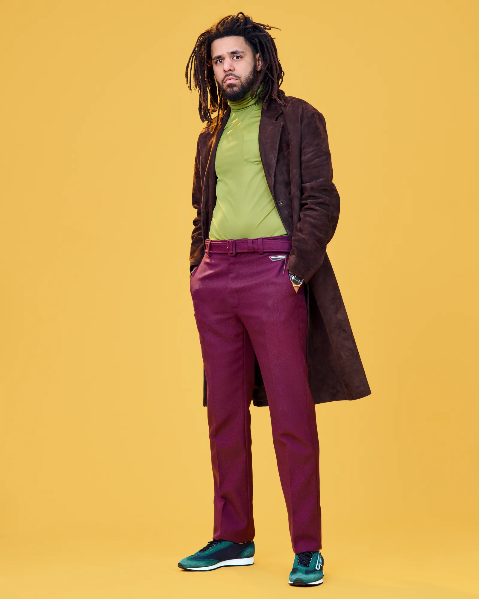 J.cole posing behind a yellow background